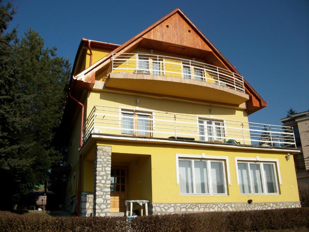 ein gelbes Haus mit Holzdach in der Unterkunft Szamóca Vendégház in Miskolctapolca