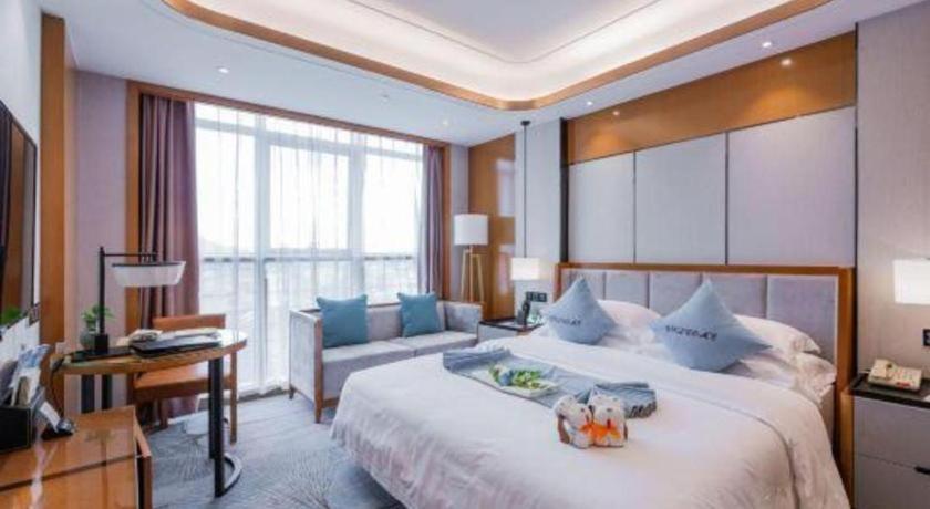 Un dormitorio con una cama grande y un sofá. en Excemon Yuyao Hemudu Hotel, en Yuyao