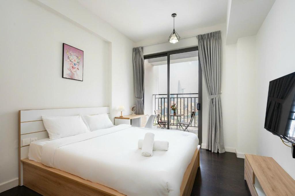 a bedroom with a large white bed and a balcony at Rivergate Residence Central in Ho Chi Minh City