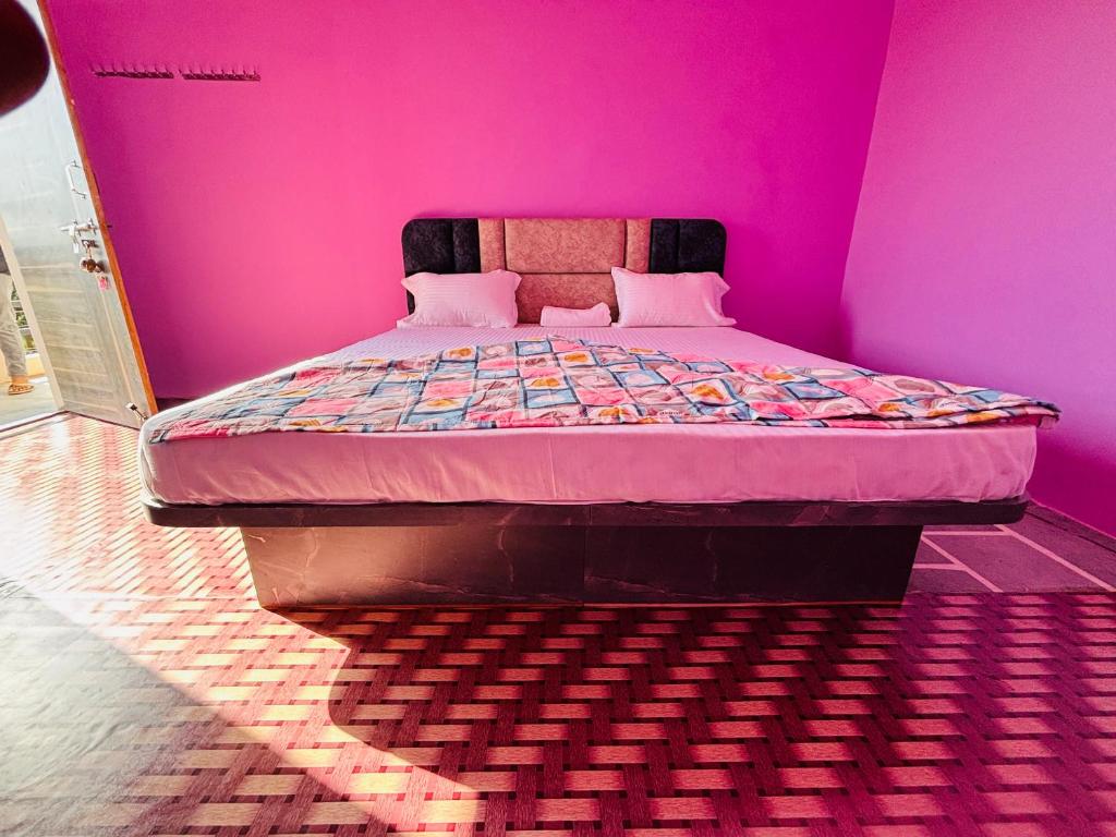 a bedroom with a bed in a pink room at Hotel Sanwariya in Degāna