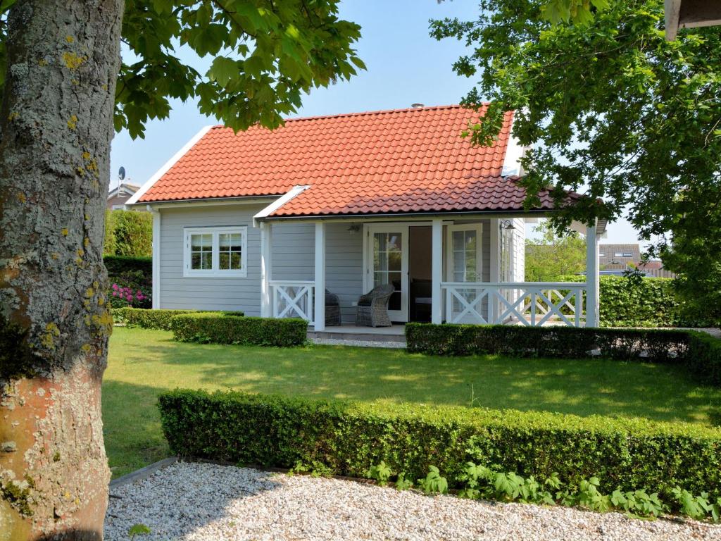 ノールトウェイクにあるStunning Holiday Home in Noordwijk near Beachのオレンジ色の屋根の白いコテージ