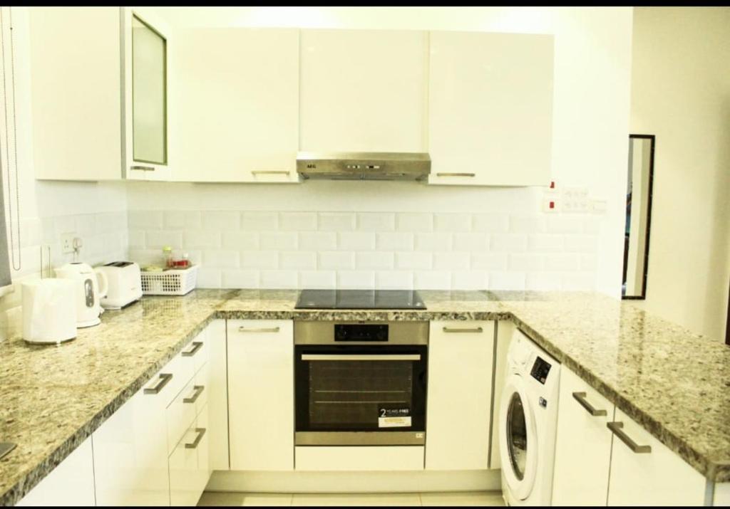 a kitchen with white cabinets and a dishwasher at Hawana Salalah in Salalah