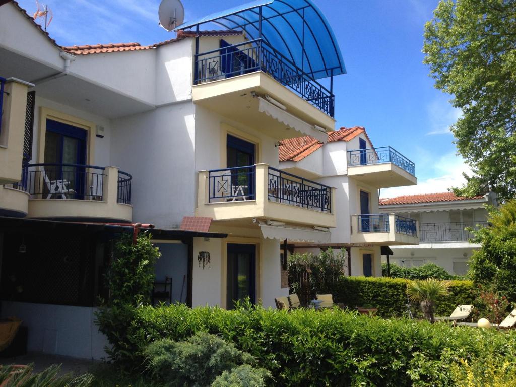 a large white house with balconies and bushes at Skala Fourkas Holiday Home in Skala Fourkas