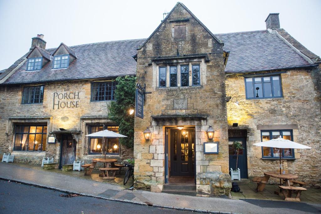 a building with tables and umbrellas in front of it at The Porch House in Stow on the Wold