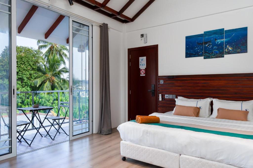 a bedroom with a large bed and a balcony at Quicksand Rasdhoo in Rasdu