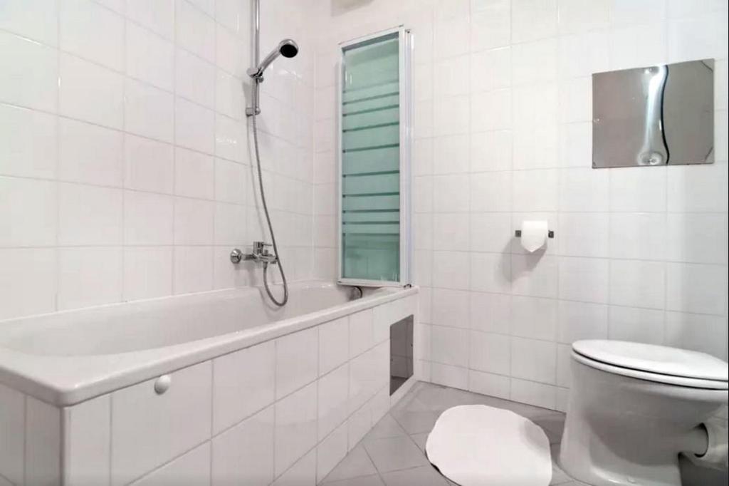 biała łazienka z toaletą i wanną w obiekcie cosy apartment in perfect location w Wiedniu