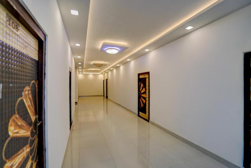 a long hallway with white walls and a painting on the wall at Spot On THE RAJA GRAND in Akbarpur