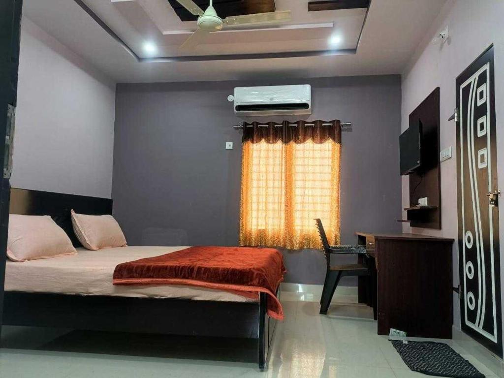 a bedroom with a bed and a desk and a window at Hotel O Shrihaan Residency in Rāmachandrapuram