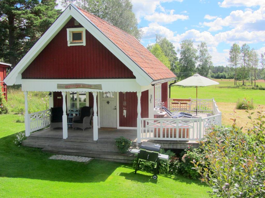 a small house with a red roof and a deck at Rensmurs Hattstuga in Sala