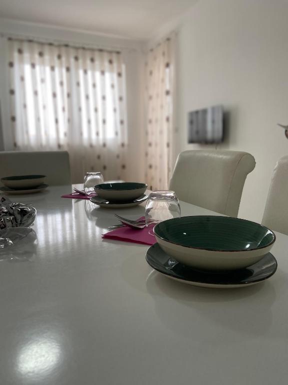 a table with two green plates and glasses on it at Fushë Kosova Apartment in Kosovo Polje