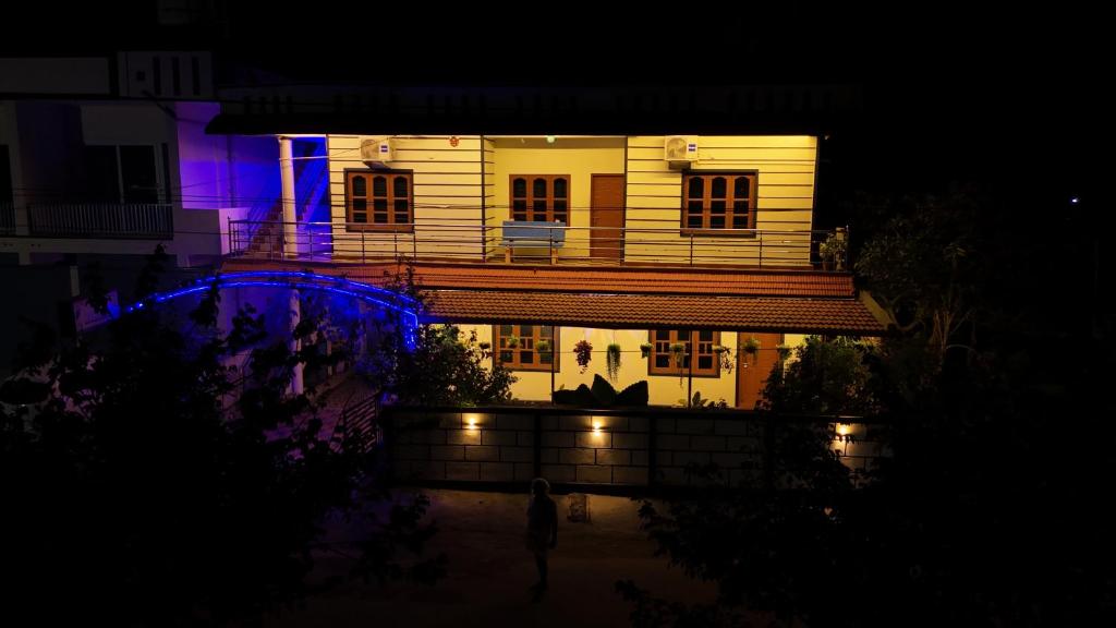 ein nachts beleuchtetes Haus mit blauen und violetten Lichtern in der Unterkunft Coorg peacock feathers home stay in Kushālnagar