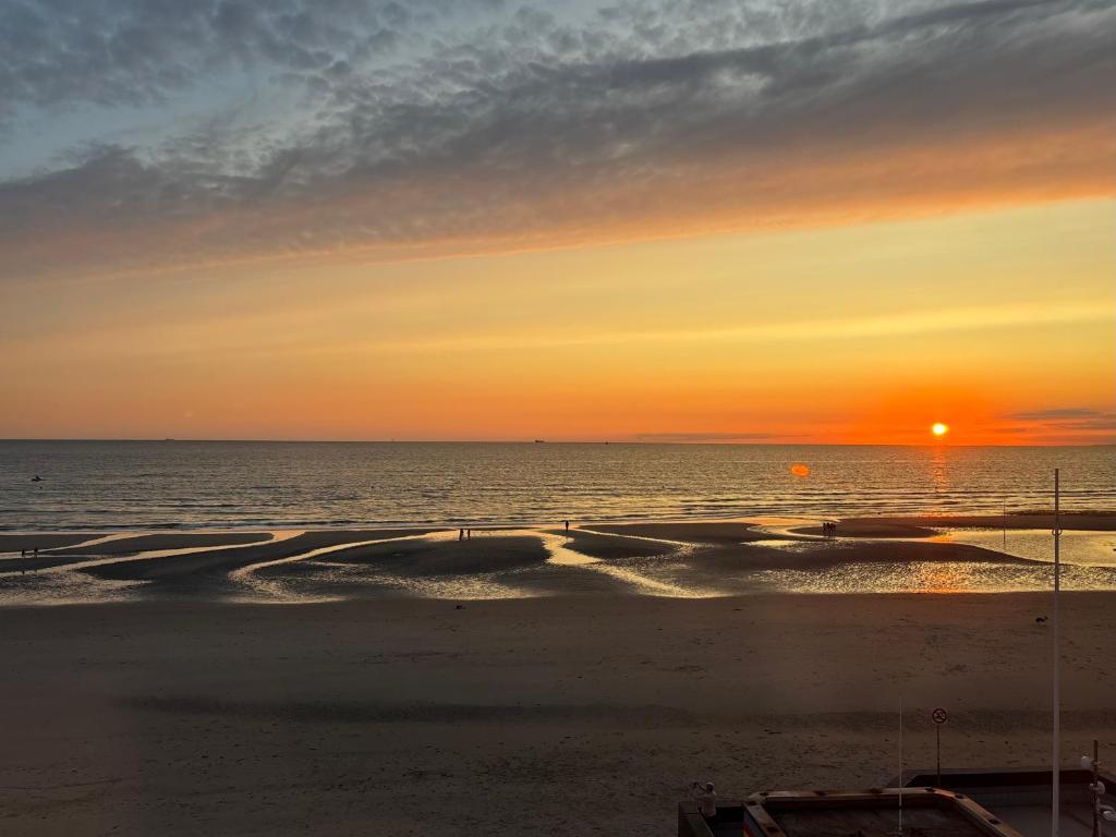 a sunset on the beach with boats in the water at T h e - P L A I C E in Wimereux