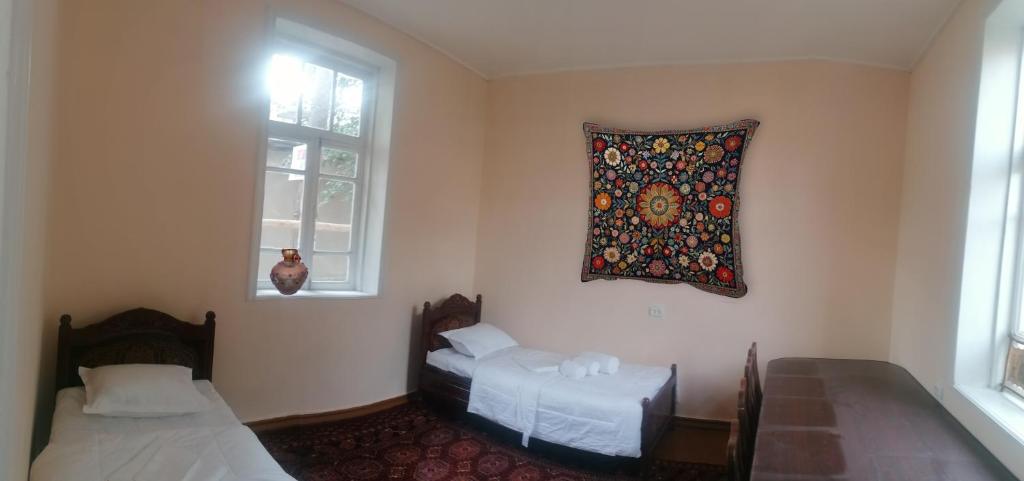 a room with two beds and a window at Qokhna Samarqand in Samarkand