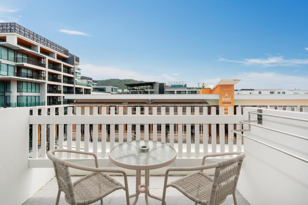 een balkon met een glazen tafel en twee stoelen bij Thawalai Inn Kata in Kata Beach