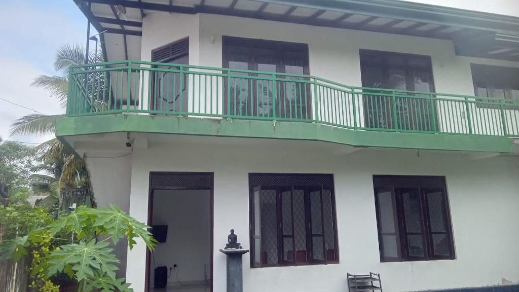 Una casa blanca con un balcón verde. en Jana Villa, en Kamburugamuwa
