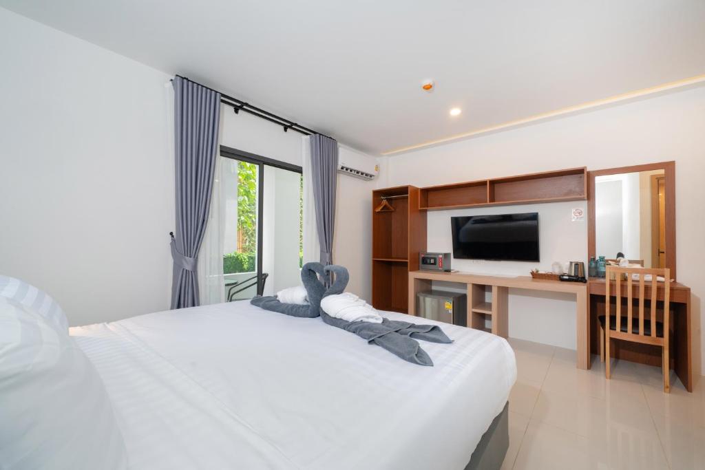 a bedroom with a bed with a desk and a television at Thawalai Inn, Kata Beach in Kata Beach