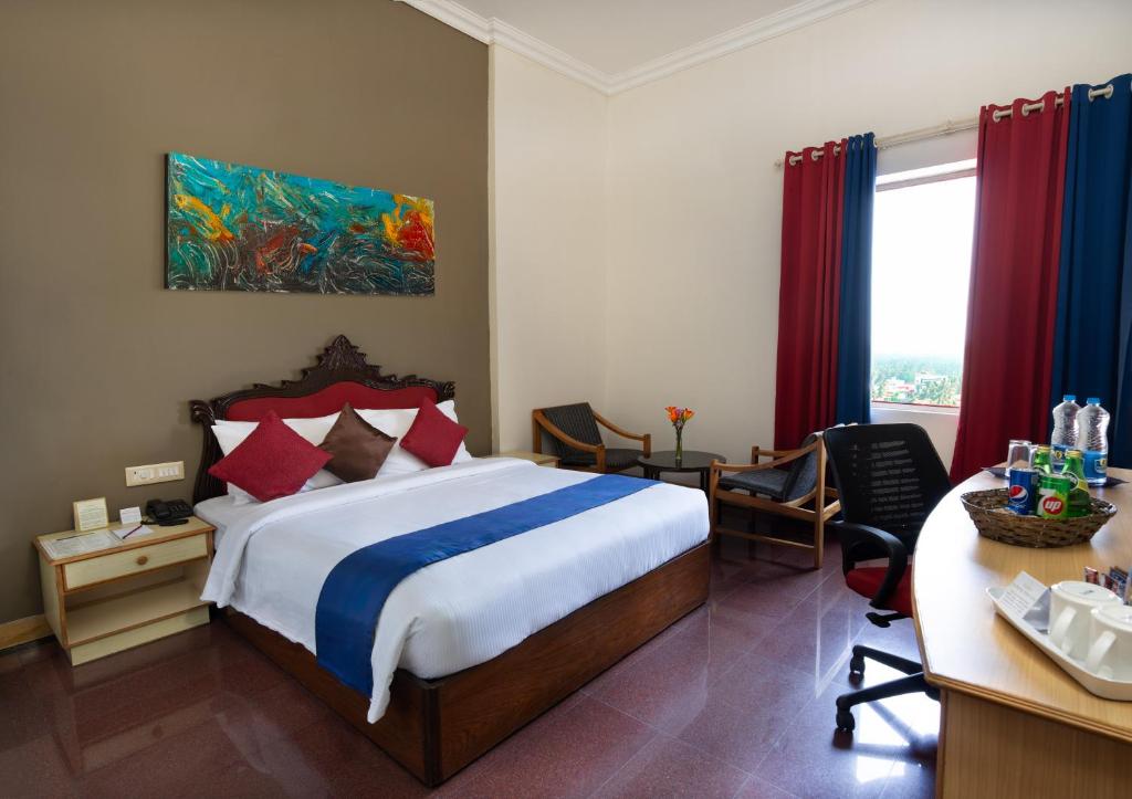 a hotel room with a bed and a desk and a desk at Presidency Towers,Kochi in Cochin