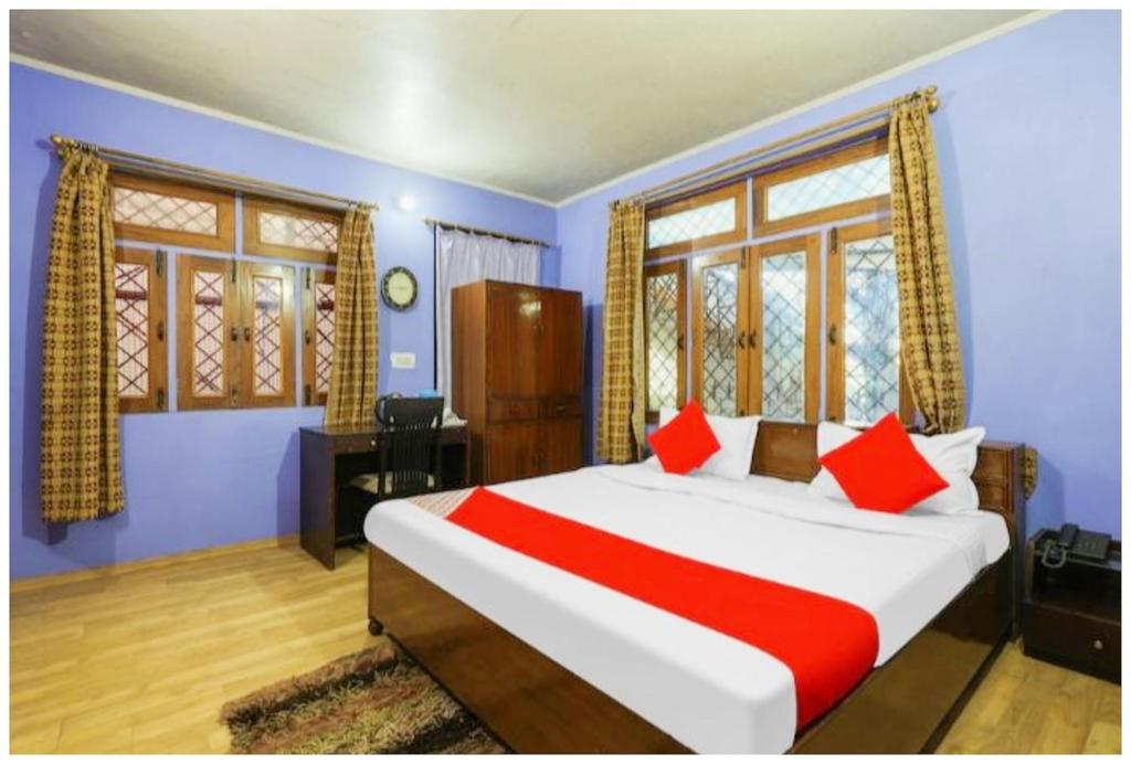 Cet appartement comprend une chambre dotée d'un grand lit, de murs bleus et de fenêtres. dans l'établissement Hotel S S- Residency Near Mall Road-NAINI LAKE - Free Parking - Jungle Safari & Restaurant Facilities - Hygiene and Spacious Room - The Best Hotel with Mountain Views, à Nainital