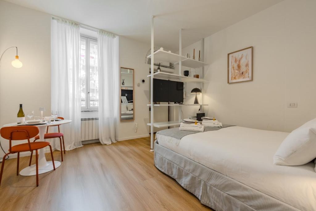 a white bedroom with a bed and a desk and a table at Naviglio Suite - Eleganza e Relax a 2 Min dalla M4 e dai Navigli in Milan