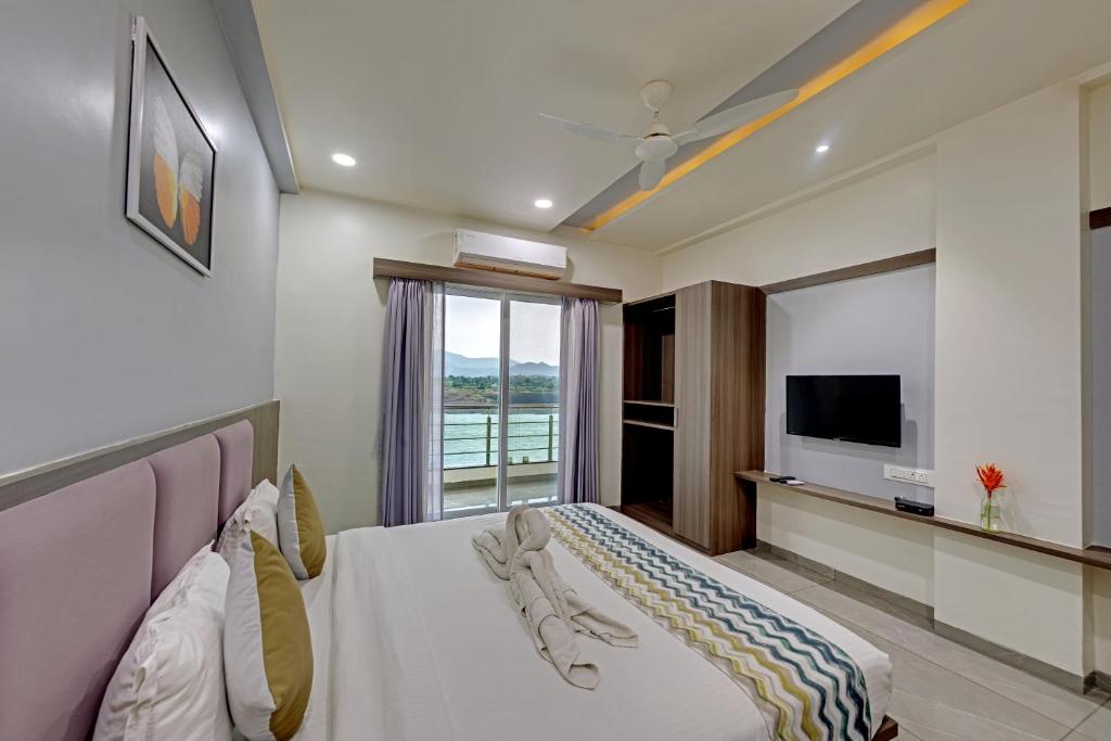 een hotelkamer met een bed en een televisie bij Sai Unity Boutique Stay in Garudeshwar