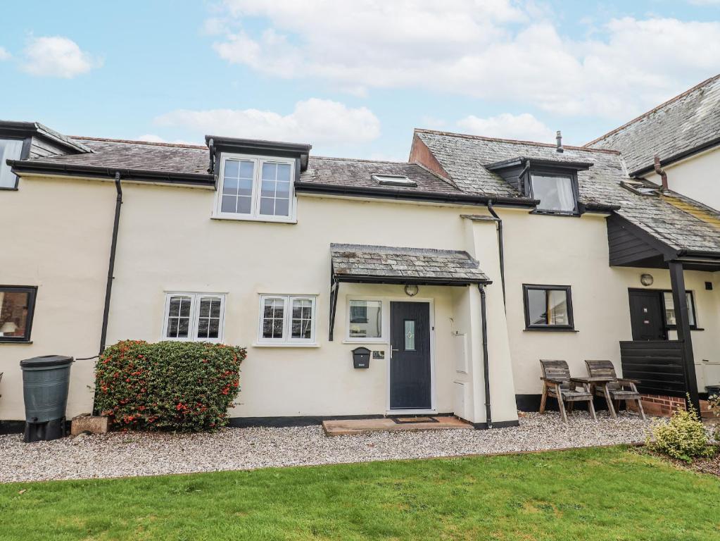 une maison blanche avec une pelouse devant dans l'établissement Rushmoor Cottage, à Colaton Raleigh