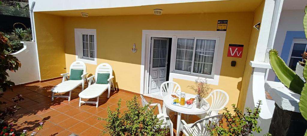 a patio with white chairs and a table and a building at Vivienda Miramar in Villa de Mazo