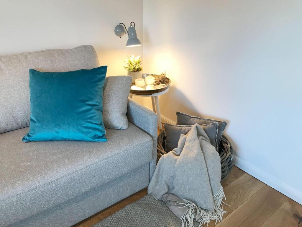 a couch with blue pillows in a living room at Ocean-View-I-Holiday-Apartments-Sylt in Rantum