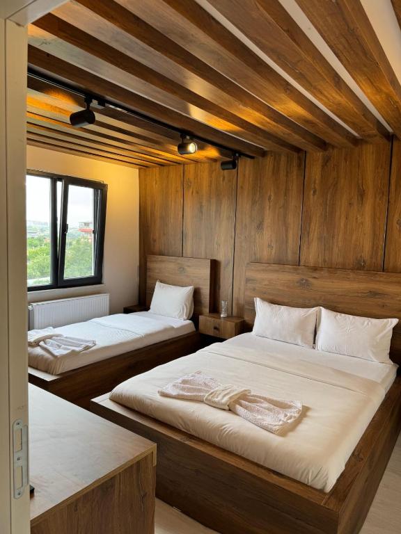 two beds in a room with wooden walls at Lina Apart in Arnavutköy