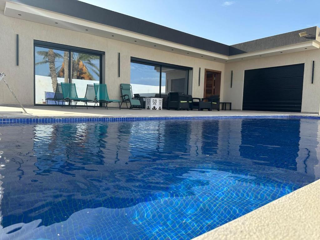a swimming pool with chairs and a house at Villa Douha in Midoun