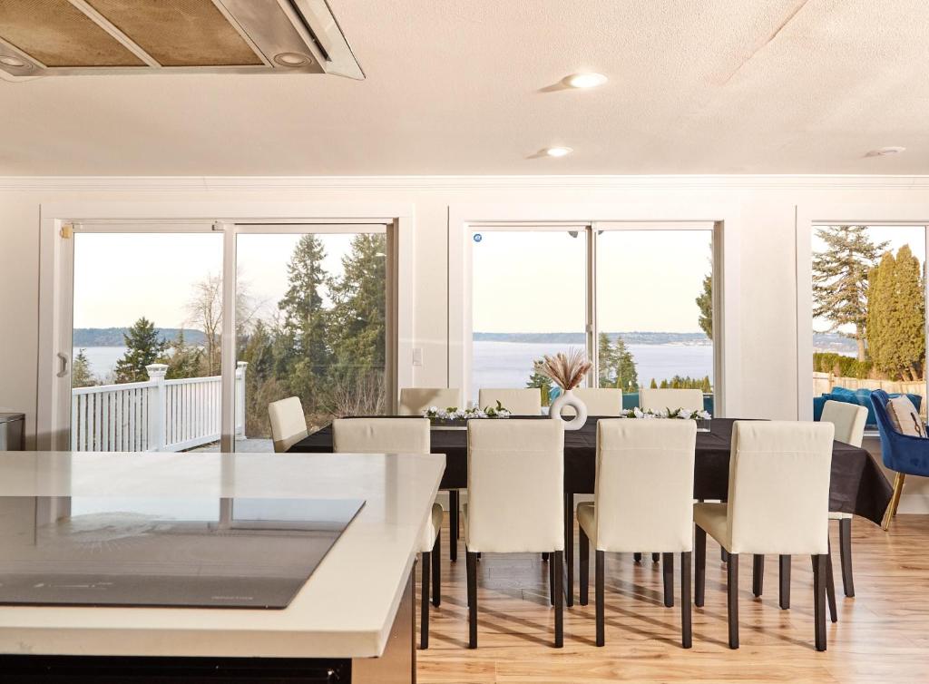 a dining room with a table and chairs and windows at Oceanline 180° home in Federal Way