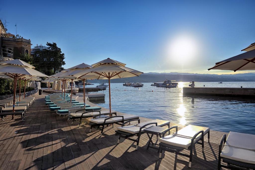 a row of chairs and umbrellas next to the water at Amadria Park Grand Hotel 4 Opatijska Cvijeta in Opatija