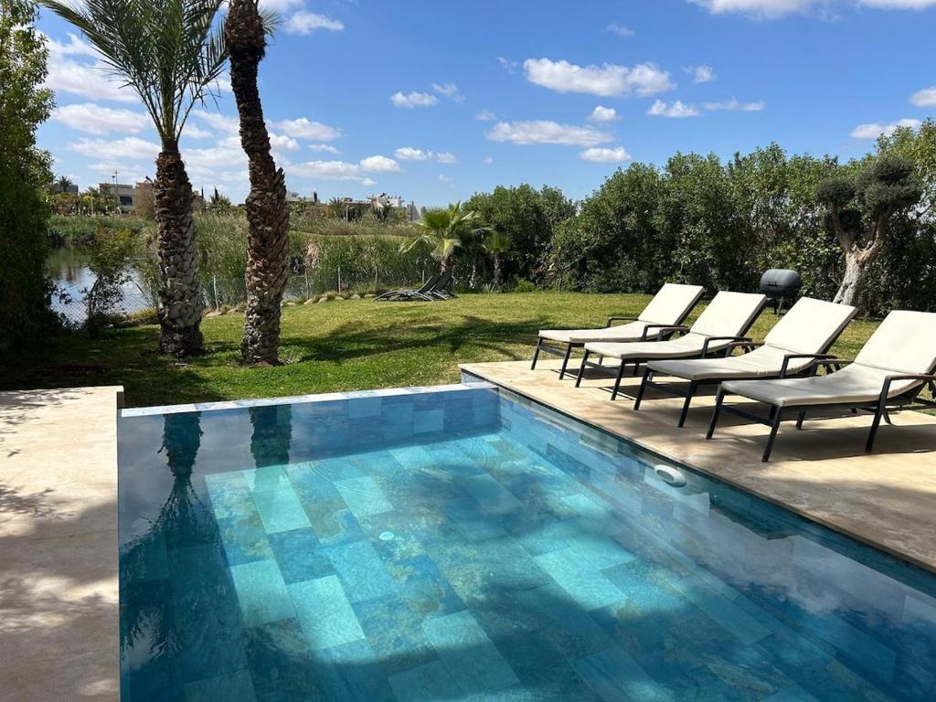 a pool with lounge chairs next to a palm tree at La source d'argan golf villa proche du centre in Marrakech