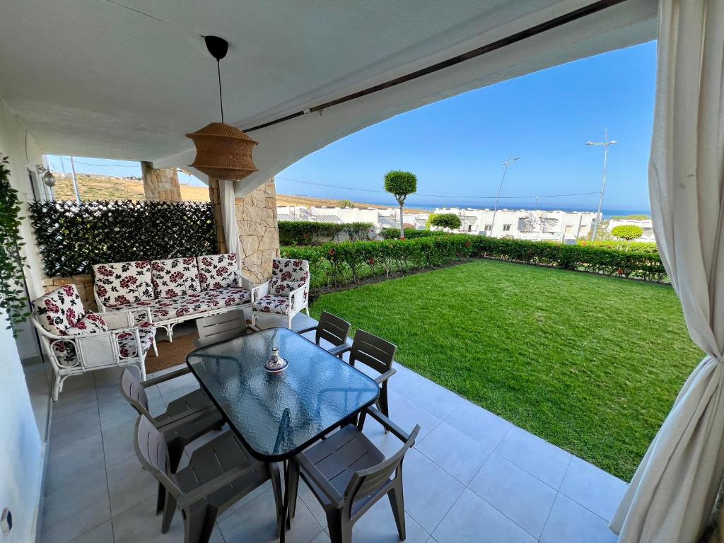 a patio with a table and chairs and a lawn at Alcudia Smir - Private Garden, Pool & Beach 8 min in Fnidek