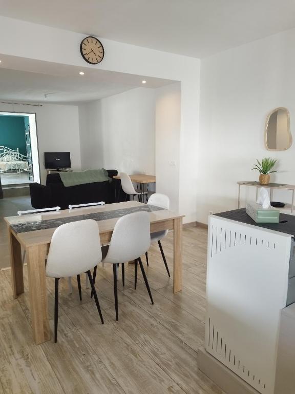 a dining room with a table and white chairs at Parfaite pour toutes direction in Fenain