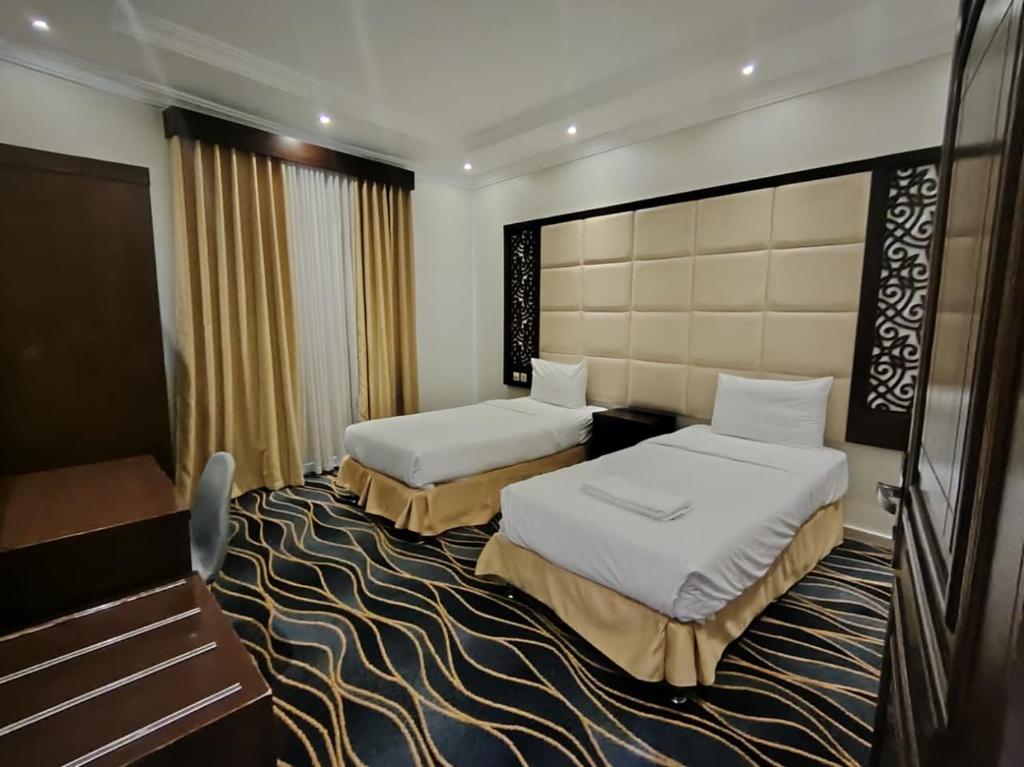 una camera d'albergo con due letti e un divano di المهاجر فرع قريش a Gedda