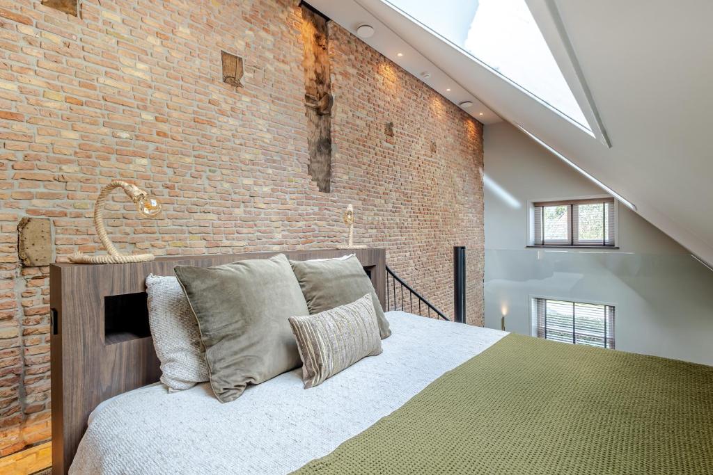 a bedroom with a bed and a brick wall at Exclusieve luxe B&B Het Renteniershuis in Molenaarsgraaf