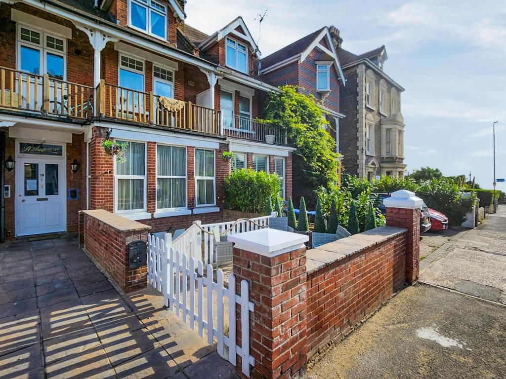 a brick house with a white fence on a street at Granville Apartment in Broadstairs