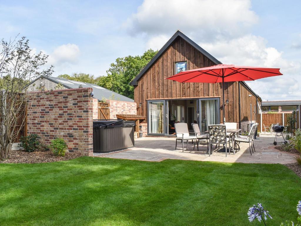 un patio con un tavolo e un ombrellone rosso di The Workshop - Uk40448 a Ferndown