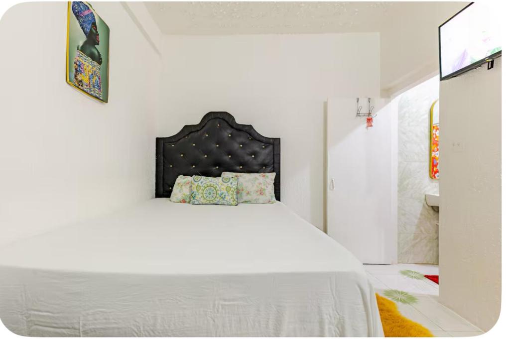a bedroom with a white bed with a black headboard at Tamaras Inn in Ocho Rios