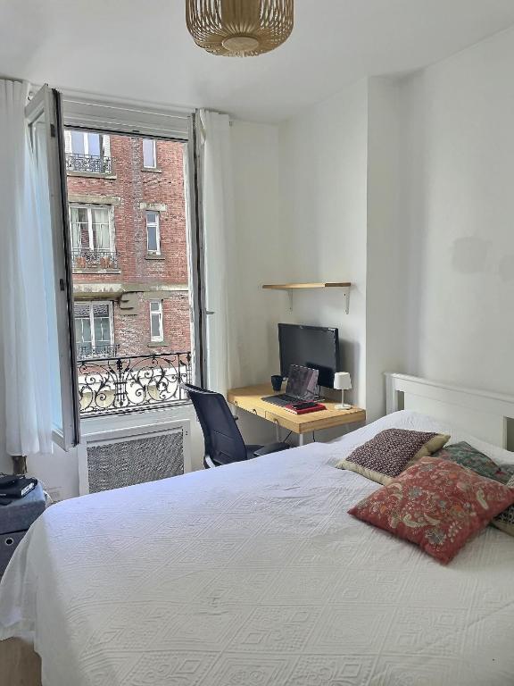 una camera da letto con un letto, una scrivania e una finestra di Appartement Chill proche Paris quartier calme proximité de toutes commodités Idéal Professionels et petite famille moins 15 pourcent long séjour a Boulogne-Billancourt
