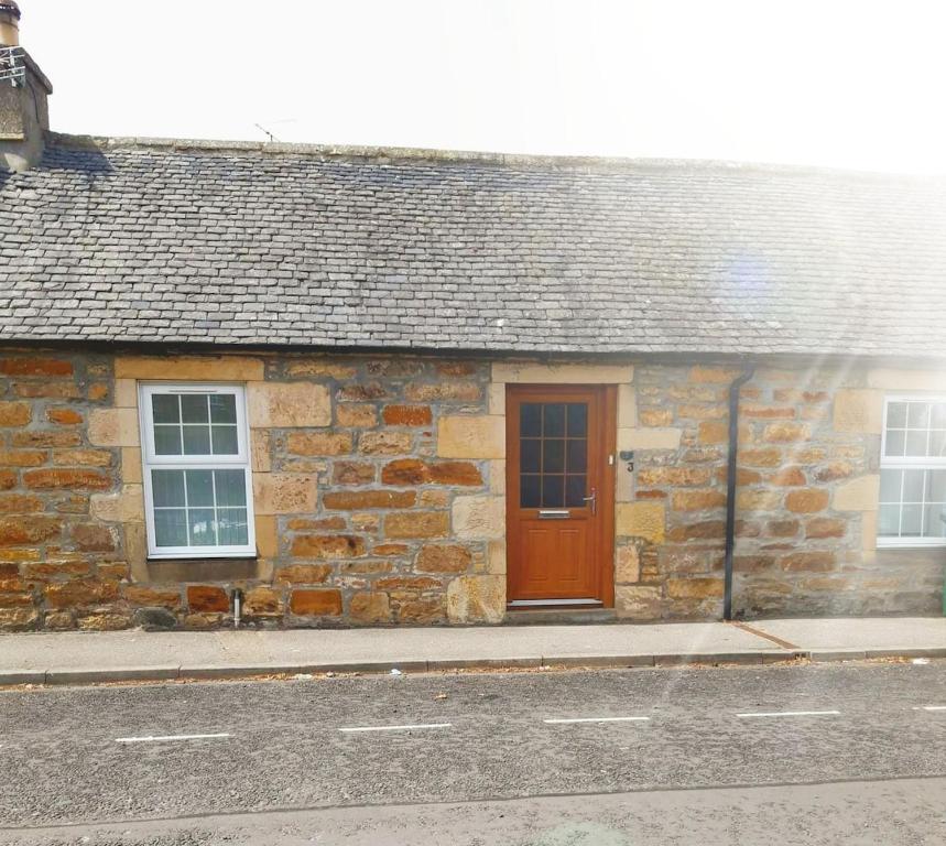 a stone house with a brown door on a street at Institution Road in Elgin