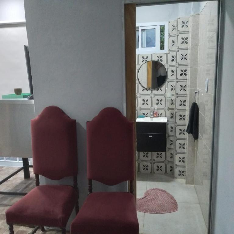 a salon with two red chairs and a mirror at Alojamiento Gra in Gualeguaychú