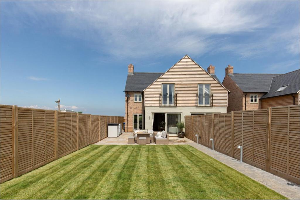a fence in front of a house with a yard at No 1 The Hides Luxury House in North Norfolk in Titchwell
