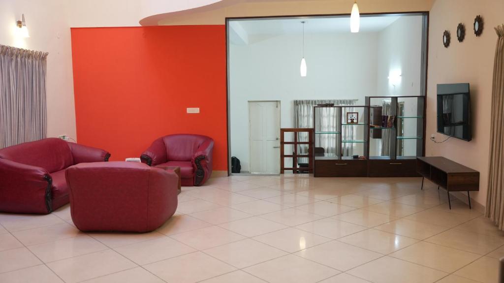 a living room with two chairs and a tv at Scenic Family Retreat in Kodai! Kodai Sierra in Kodaikānāl