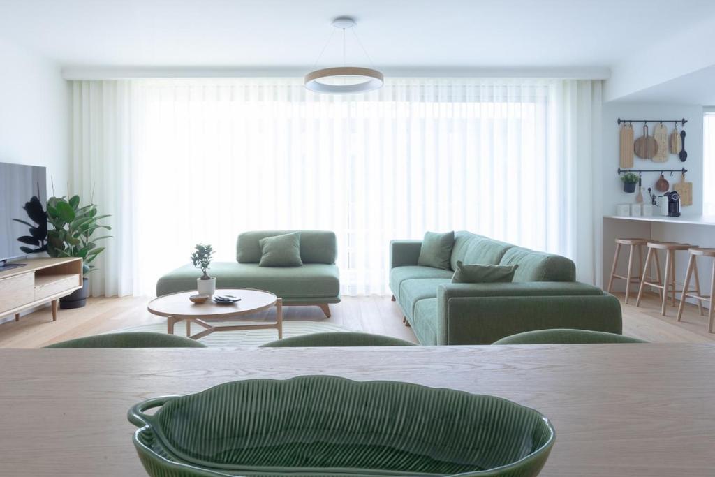 un soggiorno con 2 divani verdi e un tavolo di My Home is Yours a Porto