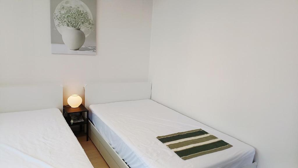 a bedroom with two beds and a vase on the wall at 무료주차 수원역차량 5분 행궁동차량7분 in Suwŏn-yŏk