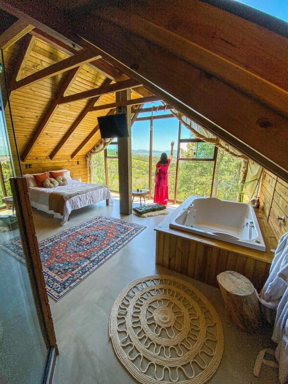 a woman standing in a room with a bath tub at Chalés do Tabuleiro, Chalé 1 in Palhoça