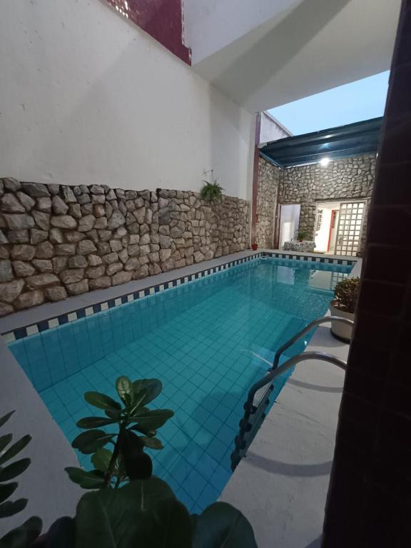 a swimming pool in a house with a stone wall at Hostel Goiabeiras in Cuiabá