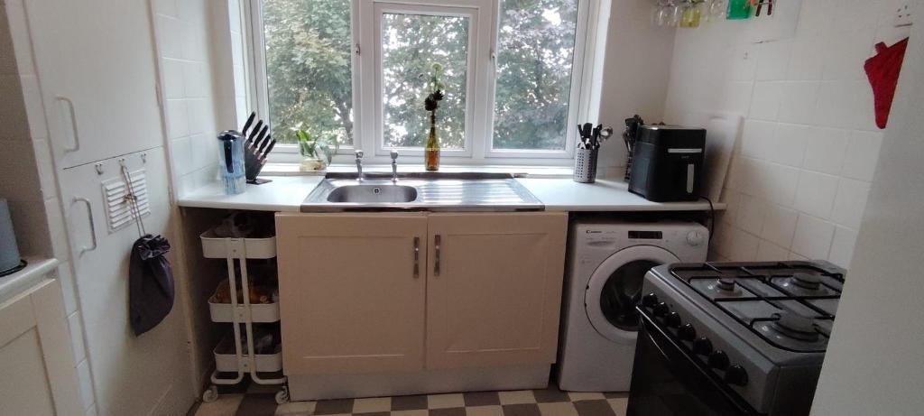 una cocina con fregadero y lavadora en Bedroom for 2 in North London, en Londres
