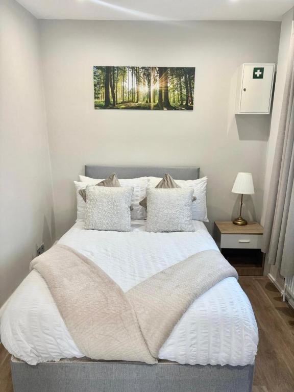 a bedroom with a large white bed with pillows at Large House Erith DA8 - 6 BDR - Sleeps up to 12 Guest - Parking - Garden - WiFi- Contractors - Families - Groups - Discounts Available for Long Term Bookings! in Erith